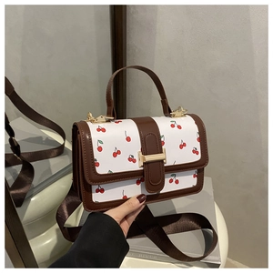 Dettaglio della borsa bianca con stampa ciliegie e tracolla marrone in stile minimal