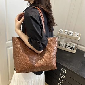 Detail of dark brown tote bag featuring a luxury woven leather texture for daily commute