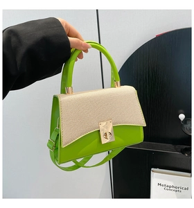 Detail of green leather and beige woven flap on small square bag with gold twist lock