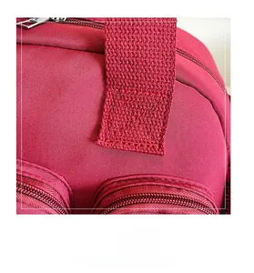 Macro detail of wine red nylon bag showing reinforced X-stitch and durable zipper hardware