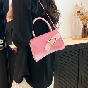 Detailed shot of pink leather handbag with gold D buckle and textured flap design
