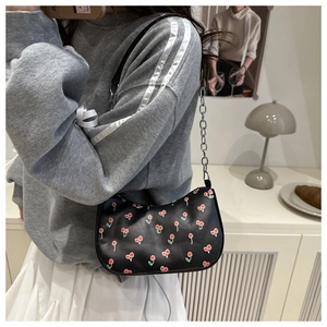 Sac bandoulière noir à motif cerises avec une élégante bandoulière en chaîne métallique argentée