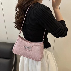 Sac sous le bras à paillettes roses avec nœud en métal argenté porté à l'épaule