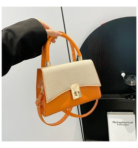 Detail of a bright orange leather and beige woven handbag with a sleek metallic twist lock