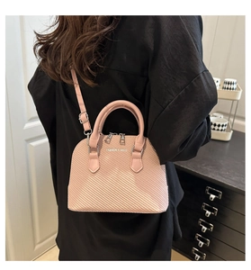 Detail of pink retro shell bag with woven texture and fashion slogan logo