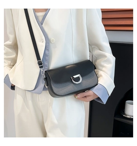 Détail du sac bandoulière bicolore avec carreaux gris, cuir noir et boucle argentée