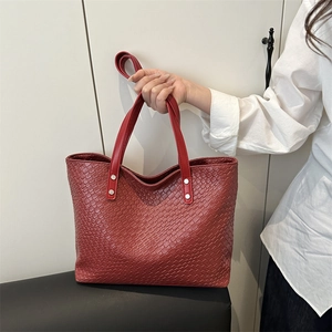 Large red woven tote bag in faux leather with silver rivets for elegant daily commuting