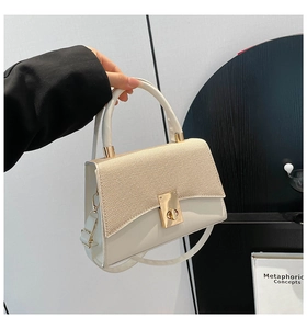 Detail of contrast stitch mini bag showing golden rotary lock and woven texture flap