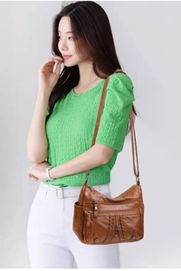 Brown faux leather crossbody bag detail featuring multiple zip pockets and textured finish