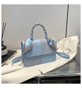 Detail of light blue patchwork handbag with floral silk scarf handle and gold hardware
