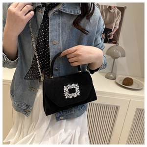 Detail of black velvet crossbody bag with rhinestone buckle and gold chain strap