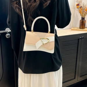 Detail of color-block handbag with gold D-buckle hardware and textured leather finish