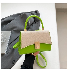 Detail of color-block handbag showing green leather, textured flap, and gold hardware