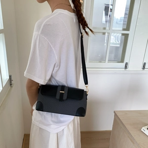 Detail of color-block crossbody bag with black leather flap and gold hardware on model