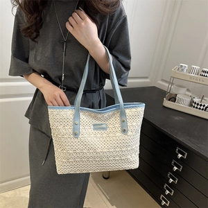 Beige hollow straw tote bag with light blue leather handles and gold rivet accents