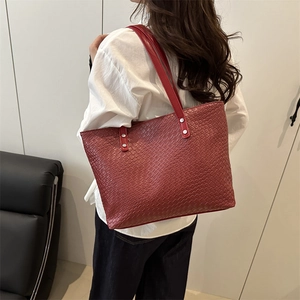 Detail of red tote bag featuring woven texture embossing and silver rivet reinforcement