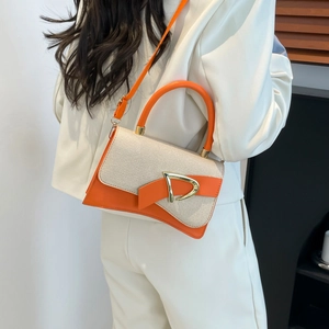 Detail of an orange and beige saddle bag with a D-ring buckle worn with a white suit