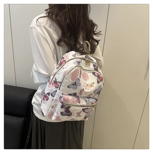 Close-up of butterfly print backpack with multiple gold-tone zippers and durable fabric