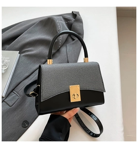 Detail of contrast stitching, grey fabric texture, and gold metal twist lock on the handbag