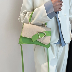 Detail of green leather handbag with beige woven panel and gold D-buckle on white suit