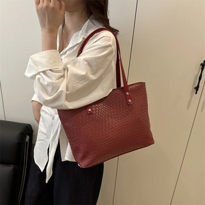Detail of red woven leather tote bag shoulder strap and premium braided texture detail