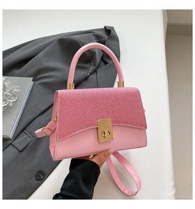 Detail showing pink contrast crossbody bag with gold twist lock and woven texture