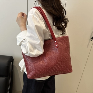 Detail of dark red woven tote bag featuring silver rivets and high-capacity commute style