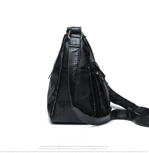 Side view detail of a black soft leather shoulder bag with multiple functional zippers