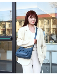 Dark blue multi-pocket crossbody bag worn by a model in casual office attire