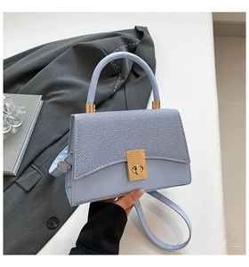 Close-up of contrast panel crossbody bag with tweed flap and gold twist-lock closure