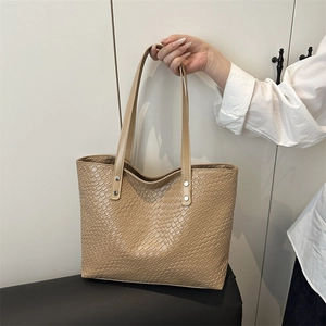 Large beige quilted tote bag with faux leather finish and metal rivets for daily commuting
