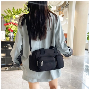 Detail of the black nylon crossbody bag with multi-pockets shown on a model