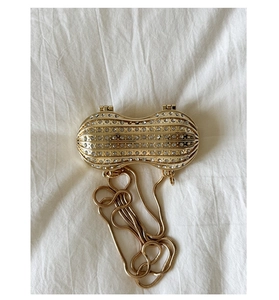 Detailed close-up of a peanut-shaped gold evening bag with sparkling white rhinestones