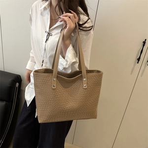Detail of khaki woven tote bag showing the fine texture and silver rivet reinforcement