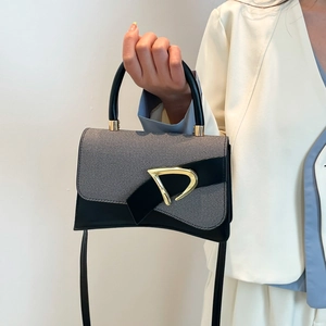 Detail of grey textured fabric handbag with black leather trim and golden D-buckle