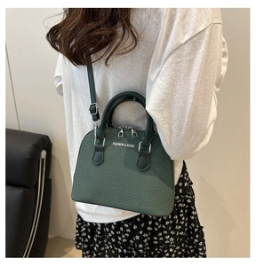 Dark green shell bag with woven texture shown on shoulder for a stylish commuter look