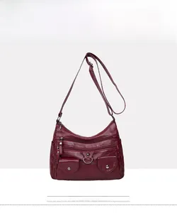 Front view of burgundy soft leather shoulder bag with multiple zippers and pockets