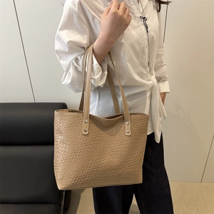 Detail of light khaki tote bag with woven texture and silver rivet on handle