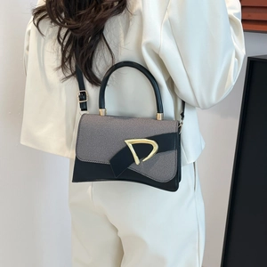 Close-up of stylish contrast bag with grey twill fabric and gold metal D-buckle detail