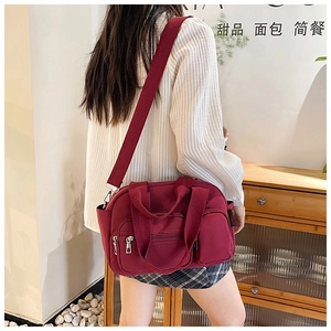 Detail of burgundy waterproof nylon bag with multiple zippers and adjustable strap