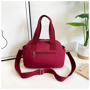 Detail view of burgundy nylon travel tote with rear zipper pocket and adjustable strap