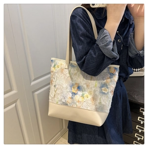 Detail of floral jacquard stitching and beige leather strap on large tote bag