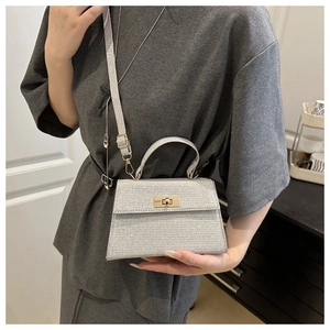 Detail of silver glitter Kelly bag featuring gold twist lock and metallic finish
