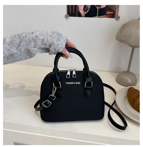 Detail of black shell-shaped handbag with ribbed texture and double round handles