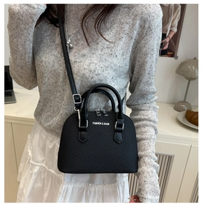 Detail of black shell-shaped crossbody bag with twill embossing and fashion text