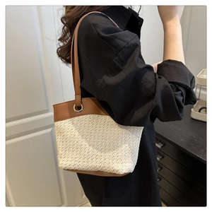 Detail view of woven straw bucket bag with brown leather handles and metal eyelets