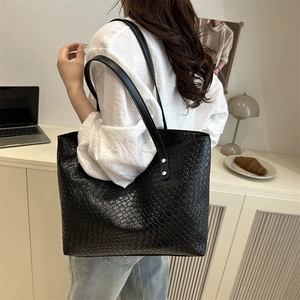 Detail of a large black woven tote bag shown in a professional office setting