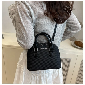 Detail of black shell crossbody bag with textured diagonal patterns and white lettering
