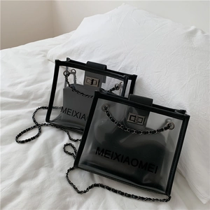 Detailed view of clear PVC crossbody bags with black leather trim and chain strap on bed