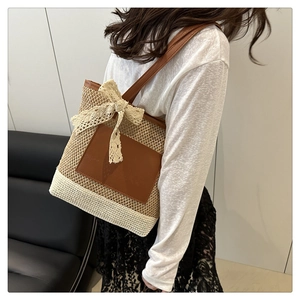 Detail of woven straw tote bag with brown leather pocket and lace bow on a model